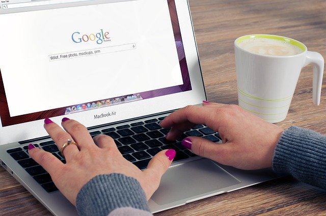 Žena s nalakovanými nechtami píše na notebooku, kde má zapnutý Google